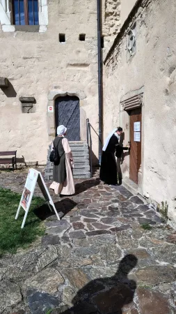 Dvě postavy v historických kostýmech procházejí zámeckým nádvořím