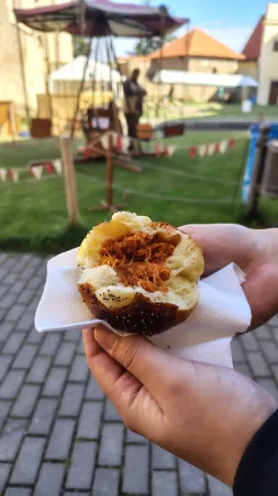 Rozpůlený mrkvanec v ruce s poutní atrakcí v pozadí