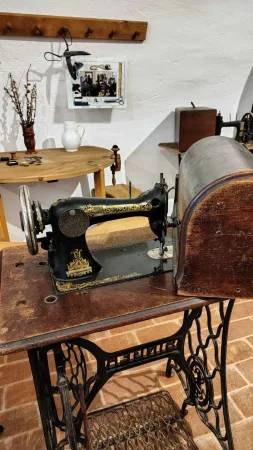 Starý šlapací šicí stroj vystavený v historickém pokoji