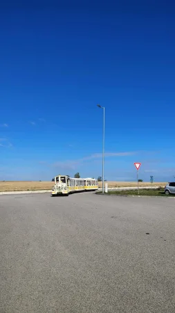 Žlutý turistický vláček projíždí po silnici mezi poli u Polné