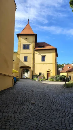 Věž zámku v Polné s cimbuřím a dlážděným nádvořím v pozadí