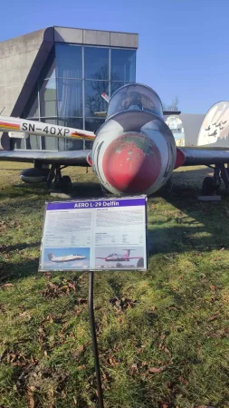 Detailní pohled na červenou přední část letounu Aero L-29 Delfin s popisnou cedulí.