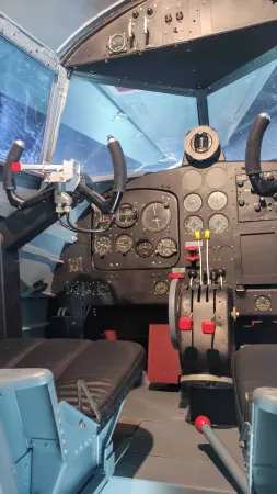Pohled do pilotní kabiny historického letadla s řídicími panely a přístroji.