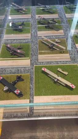 Skleněná vitrína s modely historických dvouplošníků a letadel z počátku letectví.