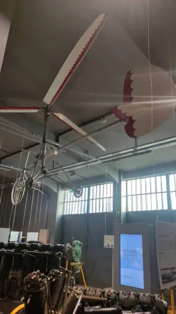 Zavěšená vrtule a křídlo raného kluzáku pod stropem muzejní haly.