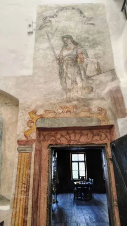 Barokní freska s ženskou postavou nad zdobeným kamenným portálem v muzeu