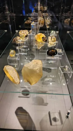 Sbírka žlutých a hnědých minerálů a broušených kamenů ve skleněné vitríně