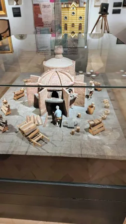 Miniaturní model kruhové cihelné pece s figurkami dělníků a hromadami cihel