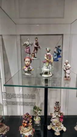 Sbírka barevných porcelánových figurek lidových postav vystavených ve vitríně
