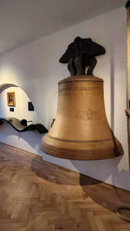 Velký bronzový zvon zavěšený na dřevěném trámu v muzejní expozici Jihlavy