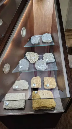 Číslované vzorky různých hornin a kamenů vystavené v muzejní vitríně