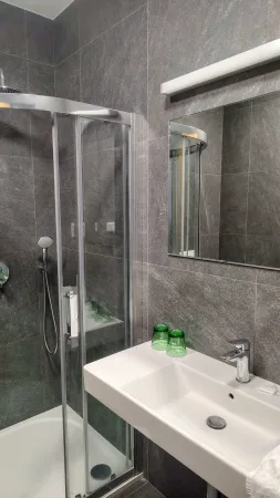 Moderní hotelová koupelna s prosklenou sprchou a umyvadlem