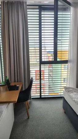 Hotelový pokoj s oknem s žaluziemi a pohledem na město