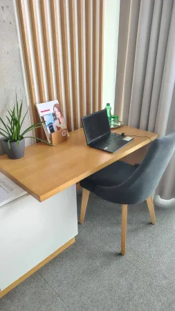 Hotelový pracovní stůl s laptopem a rostlinou u okna
