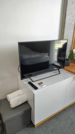 Hotelový pokoj s televizí na komodě a složenými ručníky