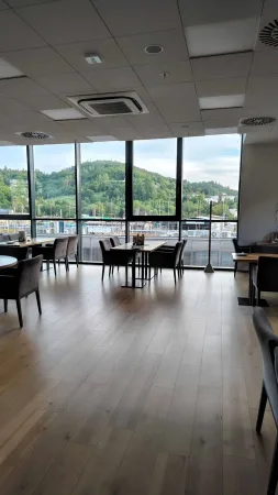 Moderní restaurace s panoramatickými okny a výhledem na zalesněné kopce