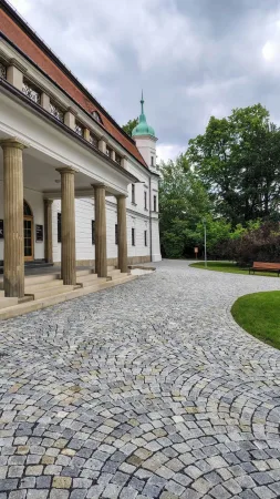 Vstupní kolonáda vsetínského zámku s dlážděným nádvořím a parkem