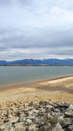 Steiniges Ufer des Sees Liptovská Mara mit Blick auf die verschneite Tatra
