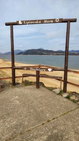 Holzschild für Liptovská Mara und Dechtáre auf dem steinernen Steg am See