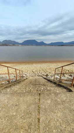 Treppe mit Geländer, die zum Seeufer hinunterführt