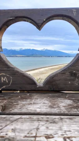 Blick durch ein hölzernes Herz auf den See Liptovská Mara und die verschneite Tatra