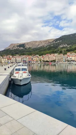 Kotvící člun v přístavu s výhledem na barevné domy Bašky