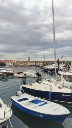 Marina s kotvícími plachetnicemi a siluetou města Krk v pozadí