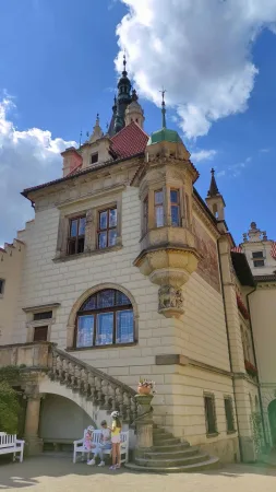 Věž zámku s návštěvníky odpočívajícími na lavičce
