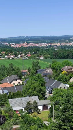 Výhled z rozhledny Hýlačka na domy, zelená pole a město Tábor v dálce