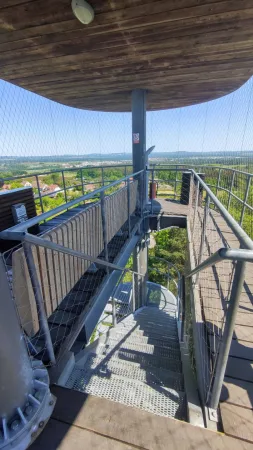 Otevřené ocelové schodiště a dřevěná plošina pod střechou rozhledny Hýlačka
