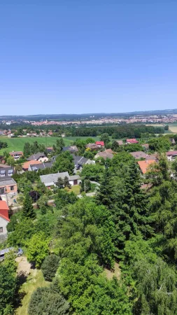 Výhled z rozhledny Hýlačka na zahrady a střechy domů s městem na obzoru