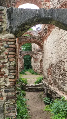 Řada cihlových kleneb a oblouků ve zřícenině Belveder s cestičkou mezi zdmi zarostlými zelení