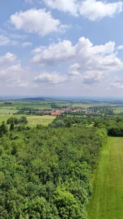 Vesnice s červenými střechami v krajině mezi lesy a poli při pohledu z rozhledny Vysoká