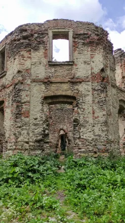 Obvodová zeď zříceniny letohrádku Belveder s prázdnými okenními otvory a zarostlou cestou před ní