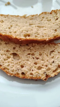 Duas fatias de pão caseiro com queijo fresco num prato branco