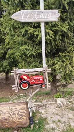 Hölzernes Ausstellungsschild mit einem Miniaturtraktor auf dem Gelände
