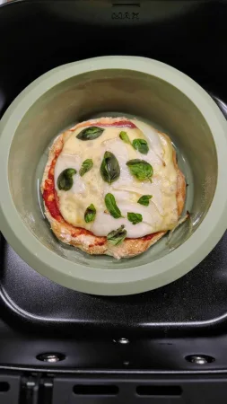 Hotová špaldová pizza s rozpuštěným sýrem a bazalkou ve formě Lékué v horkovzdušné fritéze