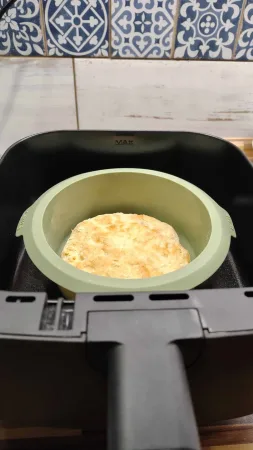 Zlatavě upečený špaldový korpus pizzy v zelené silikonové formě v koši horkovzdušné fritézy
