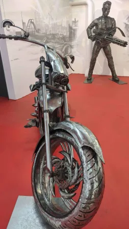 Kovová socha motorky v popředí, v pozadí socha Terminátora se zbraní.