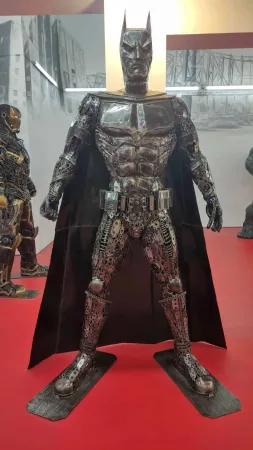 Kovová socha Batmana s dlouhým pláštěm v muzejní expozici.