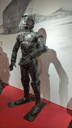 Kovová socha droida C-3PO ze Star Wars v muzejní expozici.