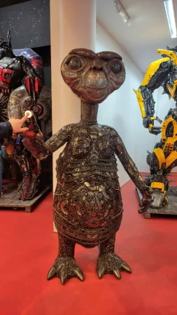 Kovová socha mimozemšťana E.T. mezi sochami Transformerů.