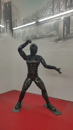 Kovová socha Spider-Mana v bojovém postoji v expozici muzea.