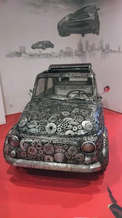 Malé kovové autíčko poskládané z ozubených koleček a šroubů.
