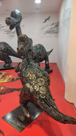 Kovová socha dinosaura raptora s otevřenou tlamou v expozici.