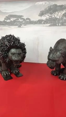 Kovové sochy lva stojící před malovanou africkou krajinou v muzeu.