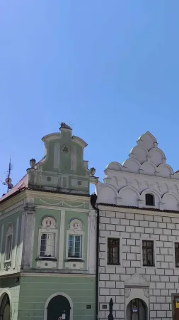 Zelený a bílý měšťanský dům se zdobenými štíty na náměstí v Táboře pod modrou oblohou