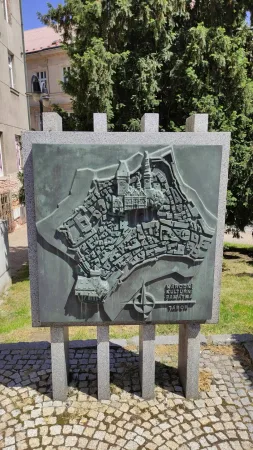 Reliéfní model historického centra Tábora na kamenném podstavci u zelených stromů a dlažby