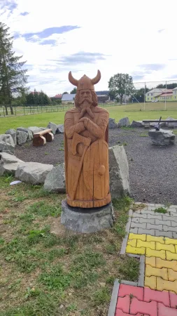 Vyřezávaná dřevěná socha vikinga se štítem stojící na kamenném podstavci