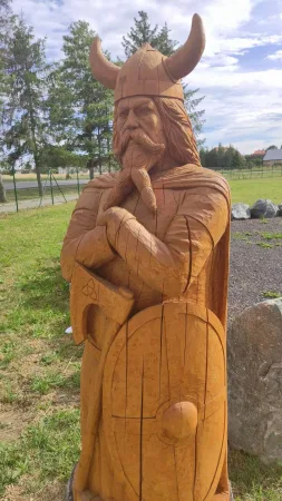 Dřevěná socha vikinga se štítem a válečnou sekerou z boku